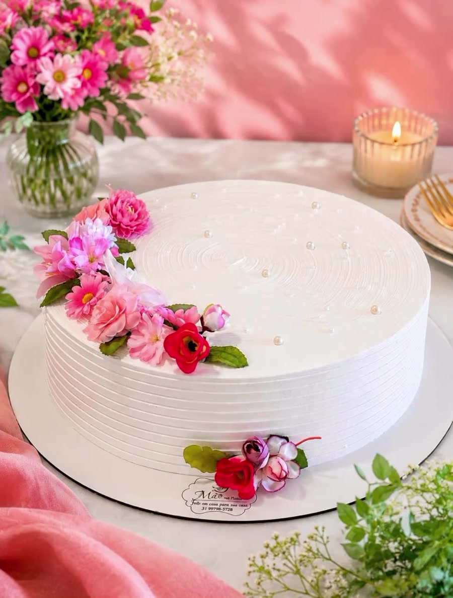 Bolo branco artesanal decorado com flores cor-de-rosa e pérolas